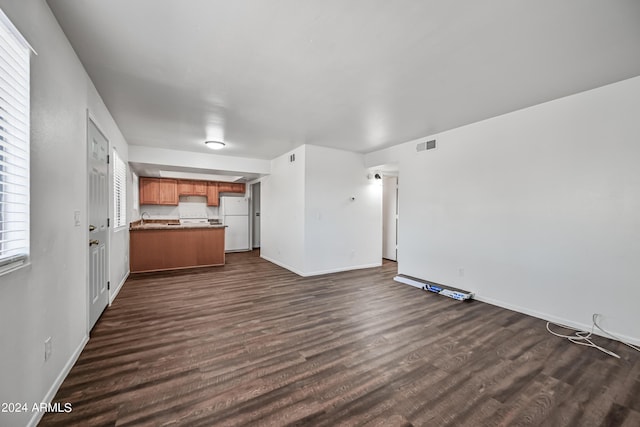 unfurnished living room with dark wood-style floors, visible vents, a sink, and baseboards