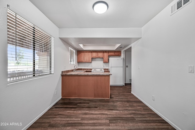 kitchen featuring white appliances, visible vents, a raised ceiling, dark wood-style flooring, and a peninsula