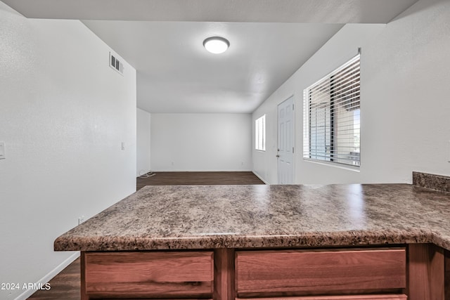 kitchen featuring a peninsula, dark wood-style flooring, visible vents, baseboards, and open floor plan