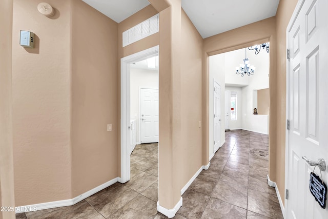 hallway with a notable chandelier and tile patterned floors