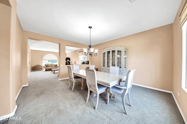 dining space featuring light carpet and a notable chandelier