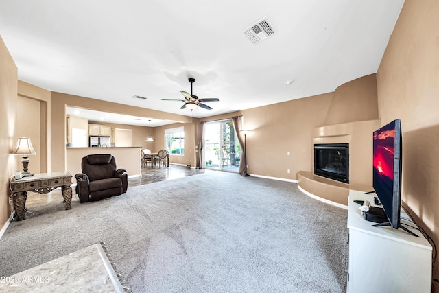 carpeted living room featuring ceiling fan and a fireplace