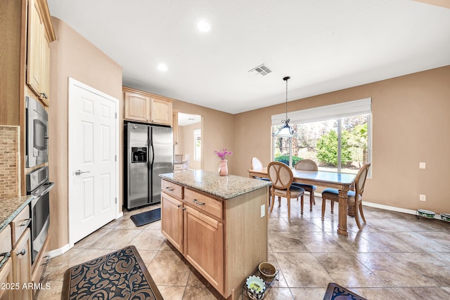 kitchen with light stone counters, light brown cabinetry, a center island, and appliances with stainless steel finishes