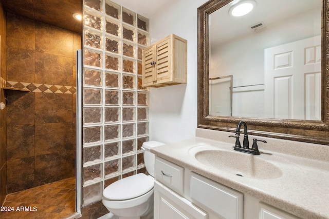 bathroom featuring tiled shower, vanity, and toilet