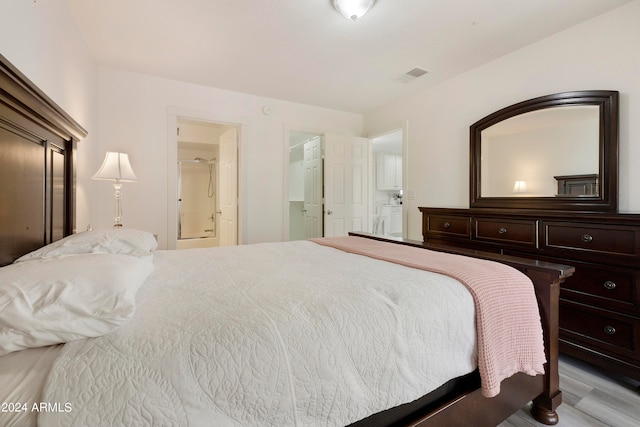 bedroom with light wood-type flooring and ensuite bath