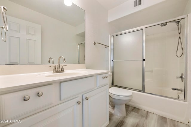 full bathroom featuring wood-type flooring, vanity, toilet, and enclosed tub / shower combo