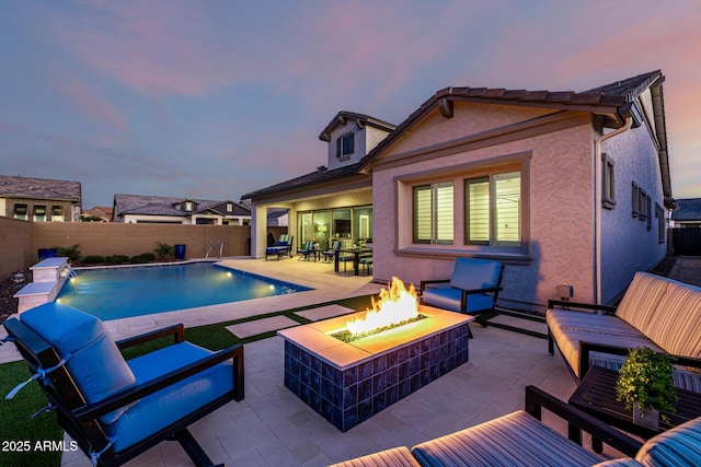 pool at dusk with an outdoor living space with a fire pit, a patio area, and a fenced backyard