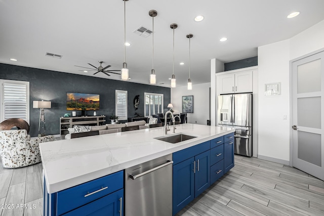 kitchen featuring a sink, appliances with stainless steel finishes, blue cabinets, open floor plan, and recessed lighting