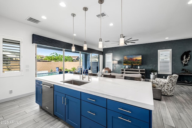 kitchen featuring a sink, blue cabinets, open floor plan, and recessed lighting