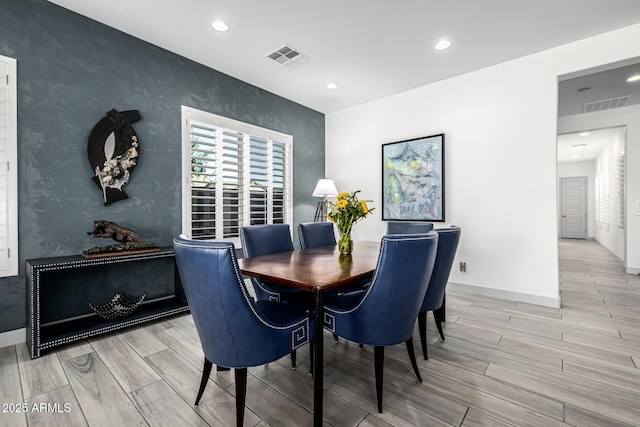 dining room with light wood-style flooring, recessed lighting, baseboards, and an accent wall
