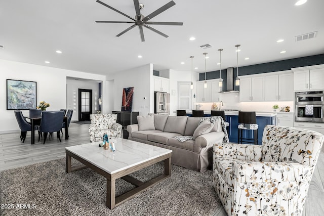 living room with recessed lighting, a ceiling fan, and light wood-type flooring