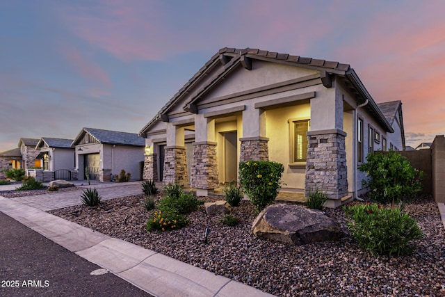 craftsman house featuring stone siding, stucco siding, driveway, a garage, and fence