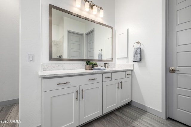 full bathroom featuring baseboards, vanity, and wood finished floors
