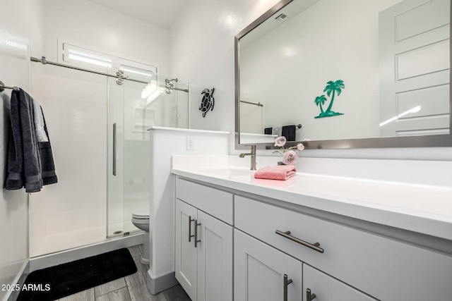 full bath with toilet, a shower stall, vanity, and wood finished floors