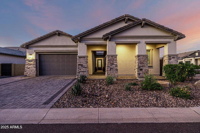 craftsman-style house with stucco siding, stone siding, decorative driveway, and an attached garage