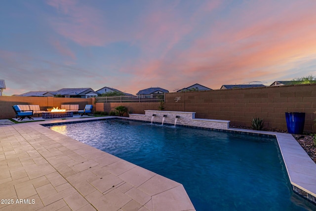 pool at dusk with a fire pit, a patio area, and a fenced backyard