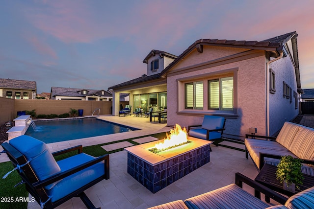 pool at dusk featuring an outdoor living space with a fire pit, a patio area, and a fenced backyard