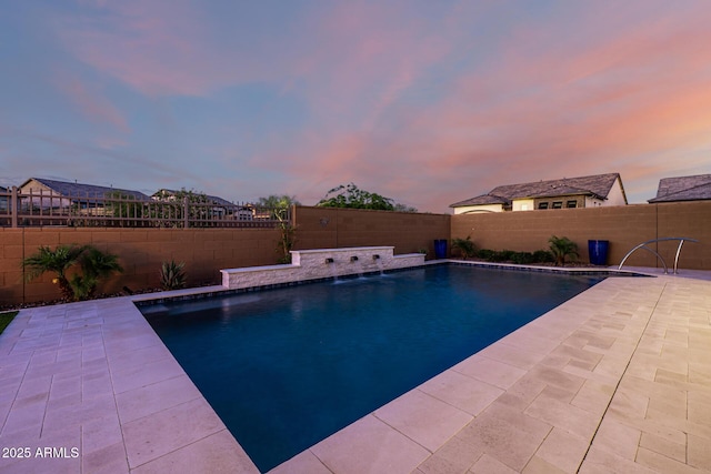 pool at dusk with a fenced backyard and a patio