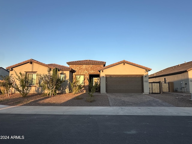 mediterranean / spanish house featuring an attached garage, a tile roof, decorative driveway, and stucco siding