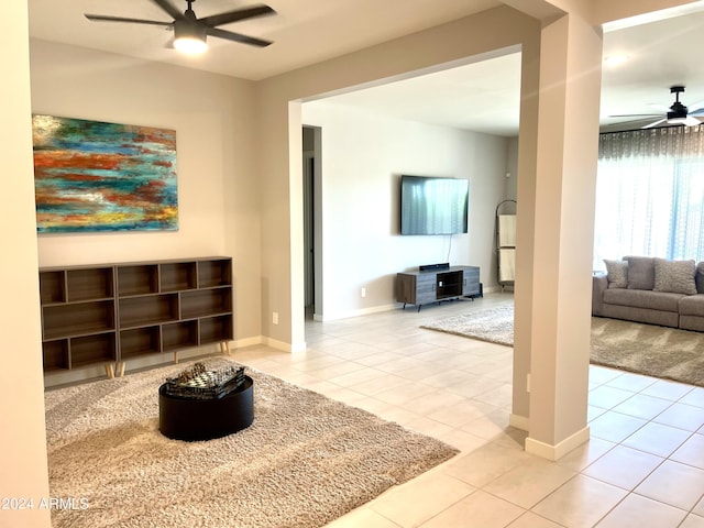 living area with baseboards, a ceiling fan, and light tile patterned flooring