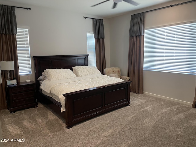 bedroom featuring ceiling fan, multiple windows, baseboards, and light colored carpet