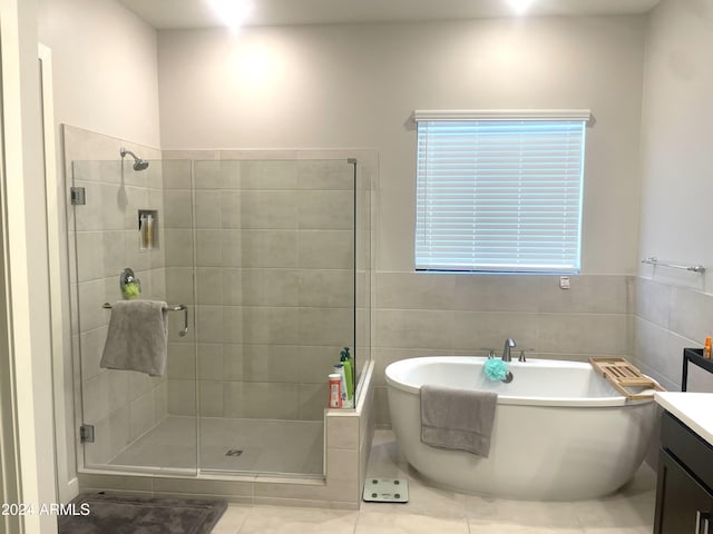 full bath featuring a stall shower, a freestanding tub, vanity, and tile walls