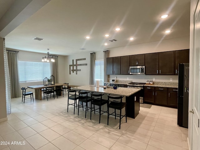 kitchen featuring a kitchen bar, visible vents, stainless steel appliances, and dark brown cabinets