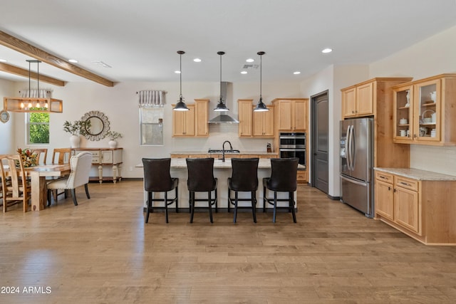 kitchen with light stone countertops, appliances with stainless steel finishes, decorative light fixtures, and wall chimney exhaust hood