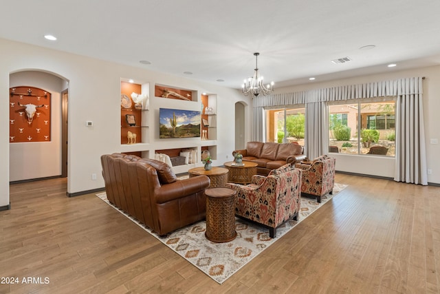 living room featuring built in shelves, light hardwood / wood-style flooring, and a chandelier