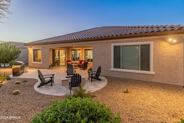 back of house with an outdoor living space with a fire pit and a patio