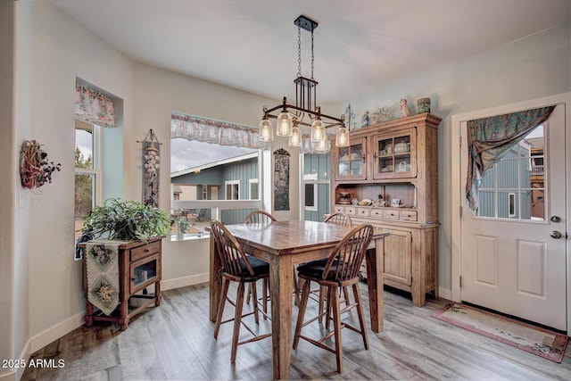 dining room with an inviting chandelier, light wood-type flooring, and baseboards