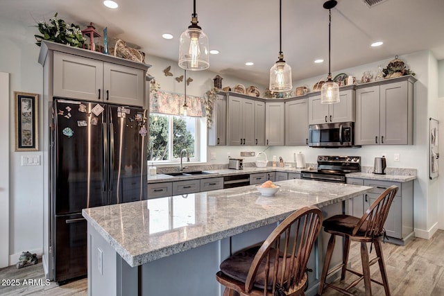 kitchen with a sink, stainless steel appliances, a kitchen bar, and gray cabinets