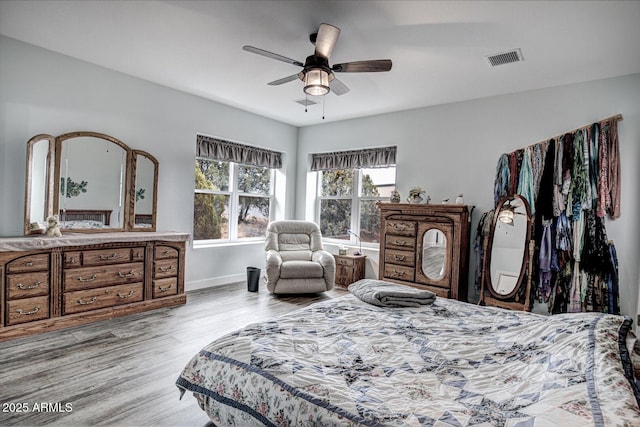 bedroom with visible vents, baseboards, wood finished floors, and a ceiling fan