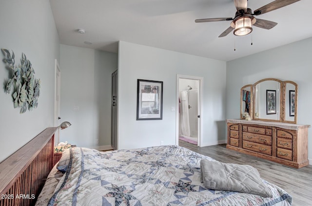 bedroom with a ceiling fan, wood finished floors, baseboards, and ensuite bathroom