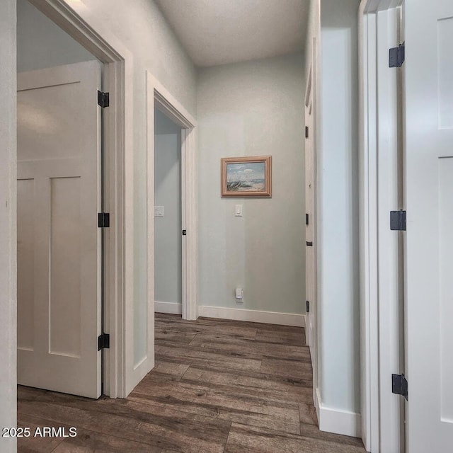 hallway featuring baseboards and dark wood-style flooring