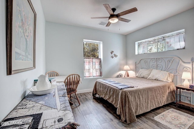 bedroom featuring visible vents, baseboards, wood finished floors, and a ceiling fan