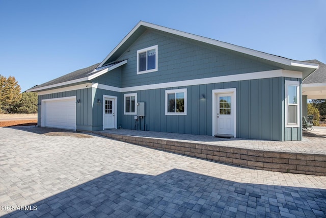 back of house with an attached garage, board and batten siding, and driveway