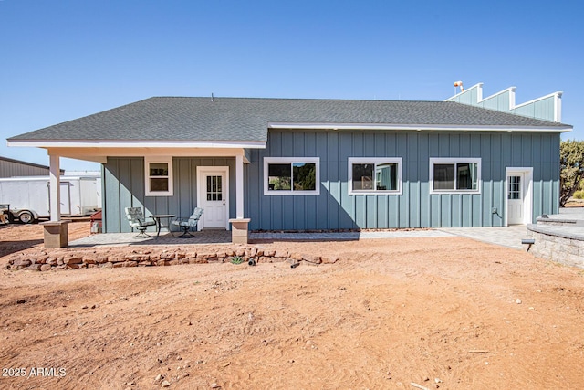 rear view of property featuring a patio, board and batten siding, and roof with shingles