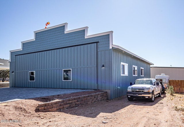 view of side of home with a patio, board and batten siding, and fence