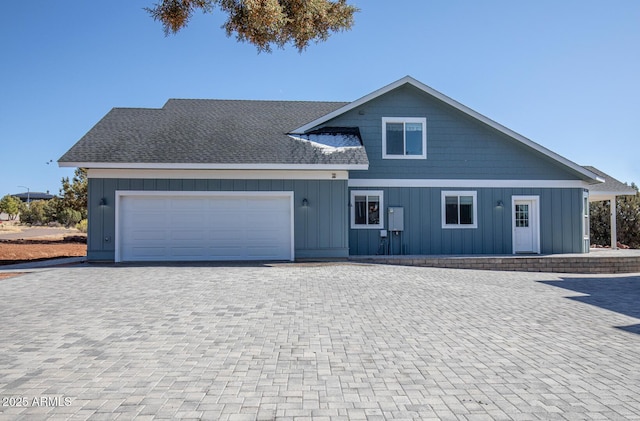 view of front of house featuring board and batten siding, a shingled roof, decorative driveway, and a garage