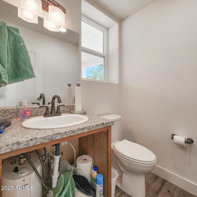 bathroom with wood finished floors, toilet, baseboards, and a sink