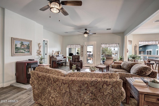 living area with visible vents, wood finished floors, baseboards, and ceiling fan