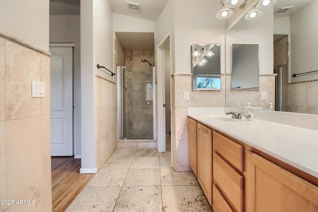 bathroom with vanity, tile walls, and an enclosed shower