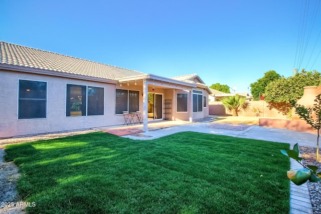 back of property with a yard and a patio area