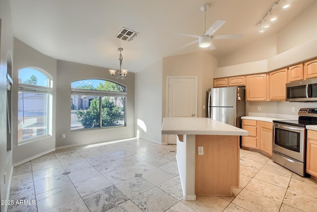 kitchen with a kitchen island, appliances with stainless steel finishes, light brown cabinets, and lofted ceiling