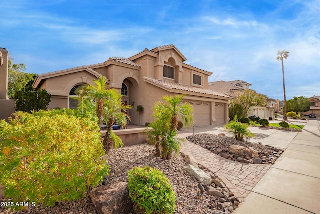 mediterranean / spanish home featuring concrete driveway, a tiled roof, a garage, and stucco siding