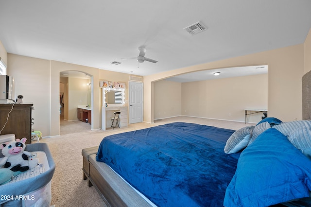 carpeted bedroom with ceiling fan, multiple windows, and ensuite bath