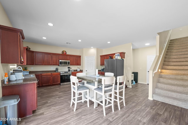 kitchen featuring appliances with stainless steel finishes, a breakfast bar, dark wood-type flooring, sink, and a center island