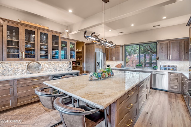 kitchen featuring decorative backsplash, light hardwood / wood-style floors, appliances with stainless steel finishes, and a center island