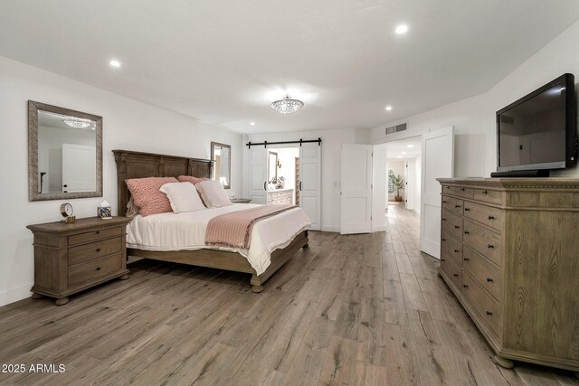 8719 E San Marino Dr, Scottsdale, AZ 85258 - bedroom with a barn door, recessed lighting, visible vents, and light wood-type flooring